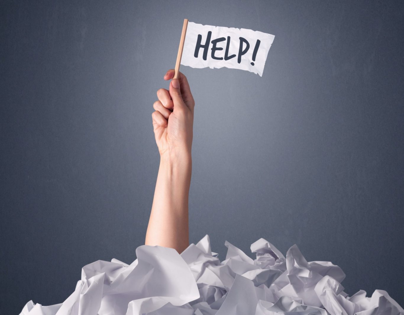 Eine Hand hält ein Schild mit der Aufschrift „HELP!“, umgeben von zerknülltem Papier. Hier fehlt Prozessoptimierung