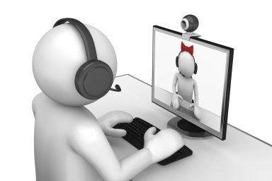 Person mit Headset am Computer, der auf einen virtuellen Charakter mit Schleife schaut.