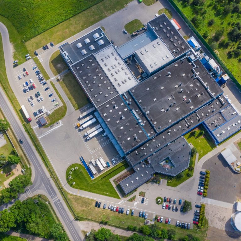 Luftaufnahme eines großen modernen Unternehmensgebäudes mit Parkplätzen.